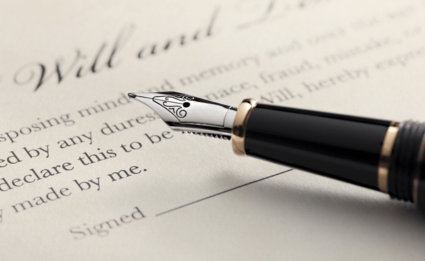 Last will and testament document with closeup on fountain pen with signature line. Critical focus on fountain pen.